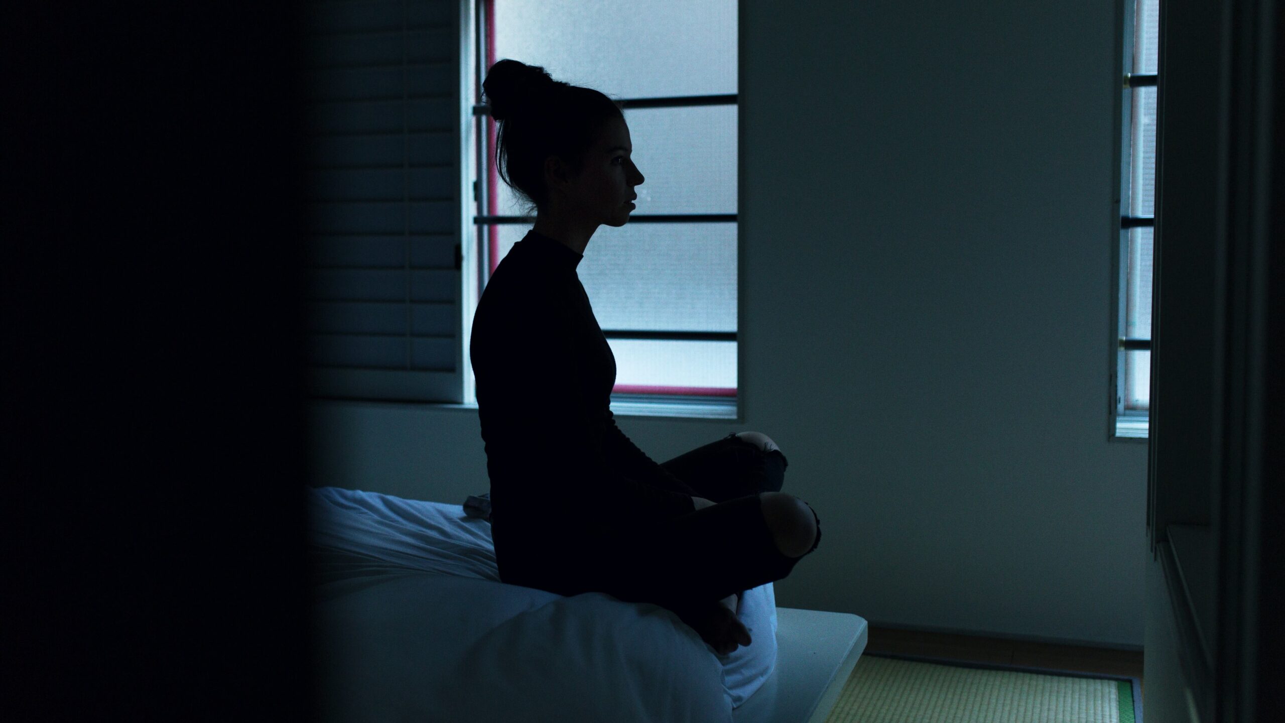 a woman is meditating on the bed, in order to easily sleep and have a healthy mind